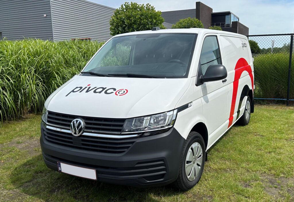 De voorkant van de bestickerde Pivaco camionette waarbij de kleuren rood, wit en zwart zijn gebruikt.