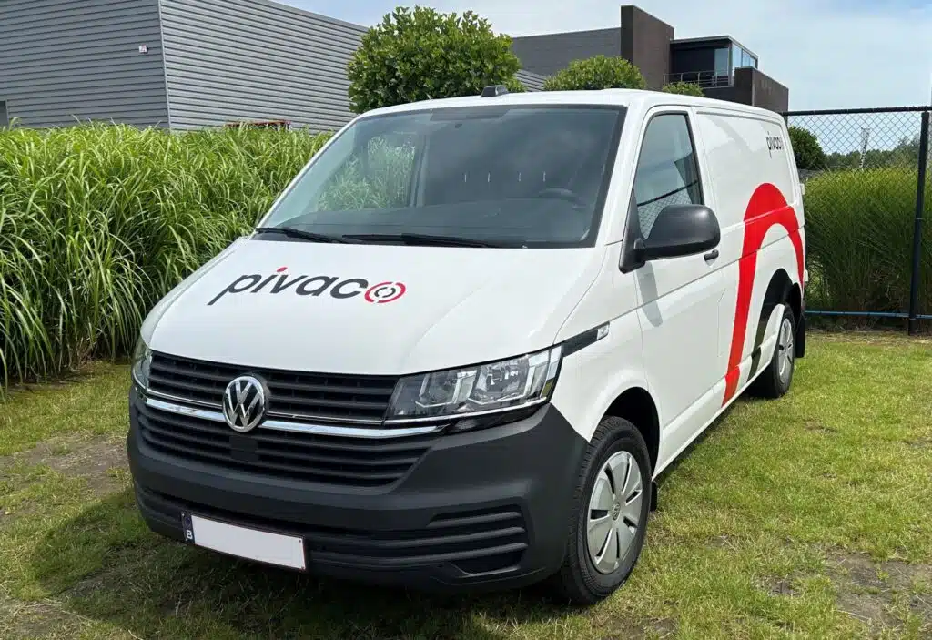 De voorkant van de bestickerde Pivaco camionette waarbij de kleuren rood, wit en zwart zijn gebruikt.