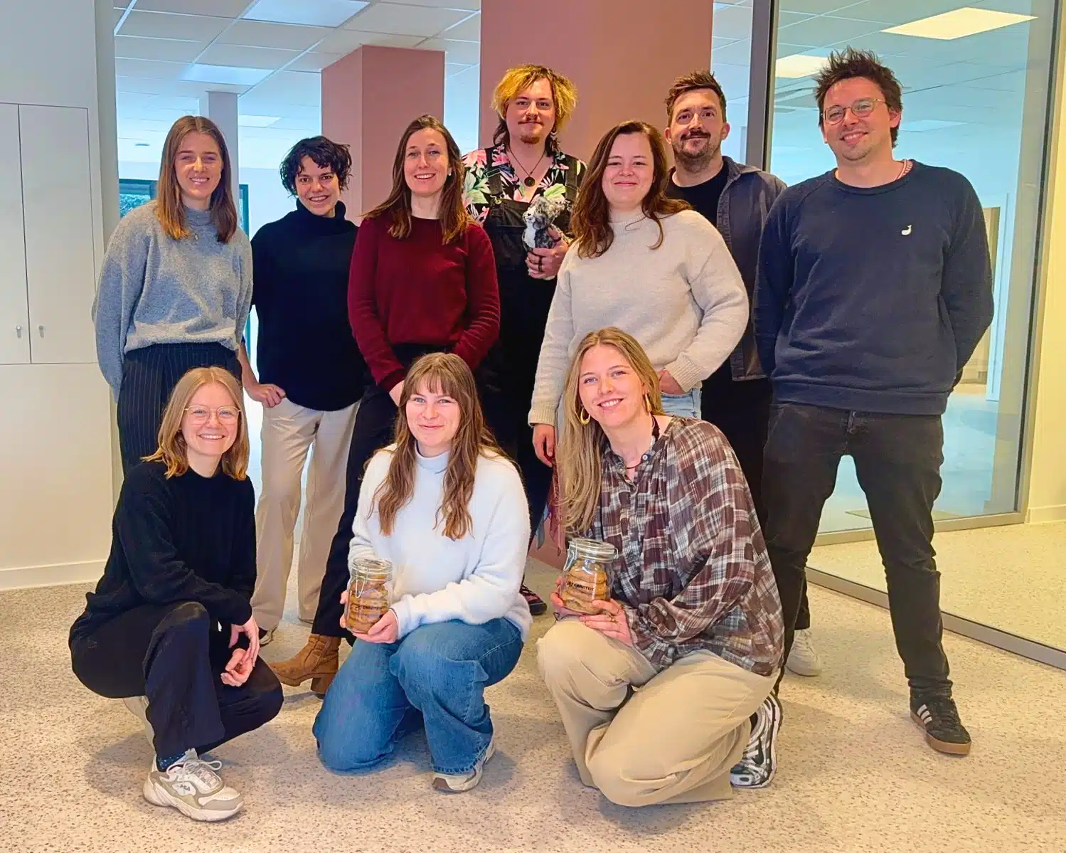 Graviteit team groepsfoto in modern kantoor - communicatiebureau medewerkers poseren samen