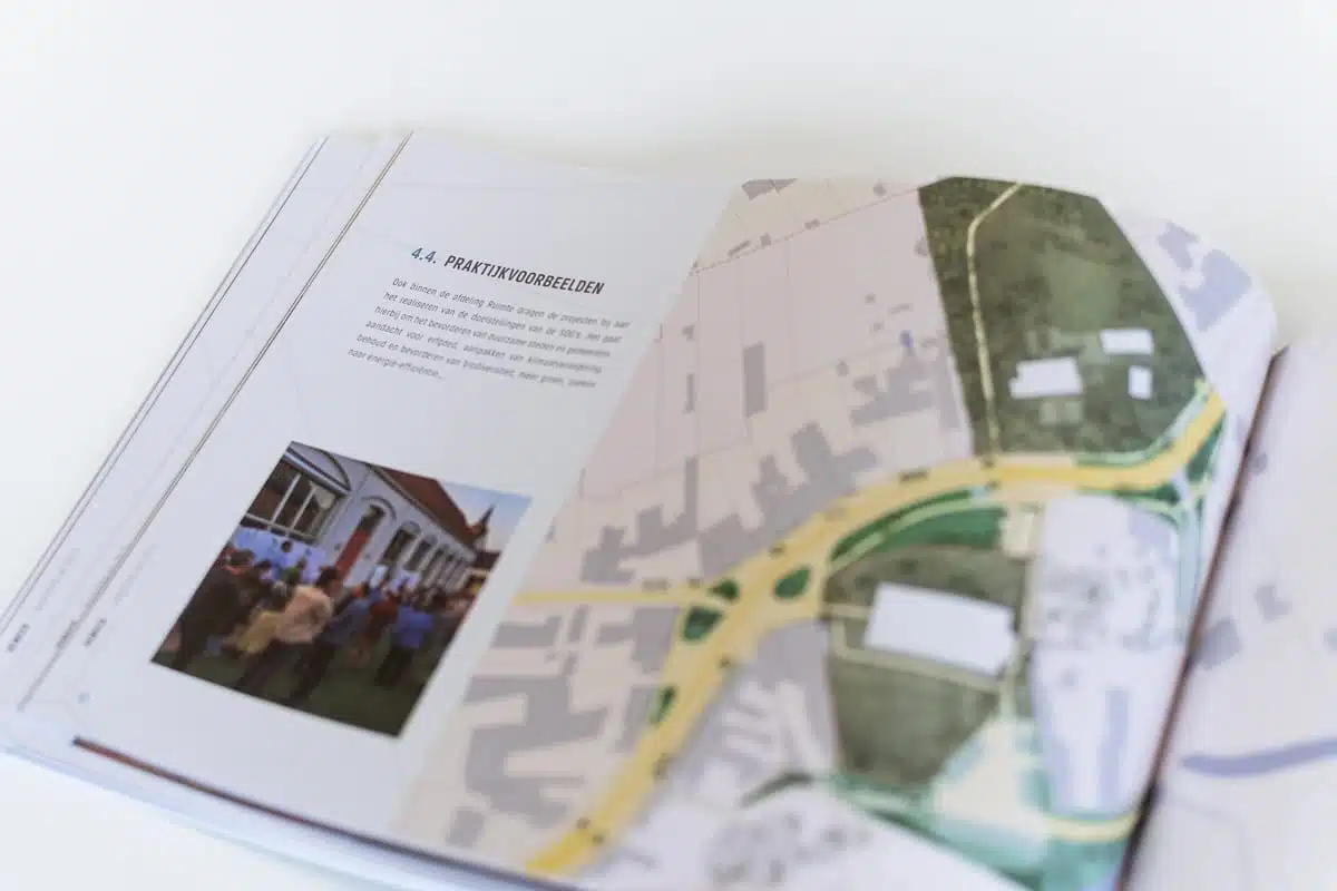 Een geopende pagina van het gedrukte jaarverslag van Veneco met een plattegrond en tekst. Onder de tekst is een kleine foto van een groep mensen voor een gebouw te zien.