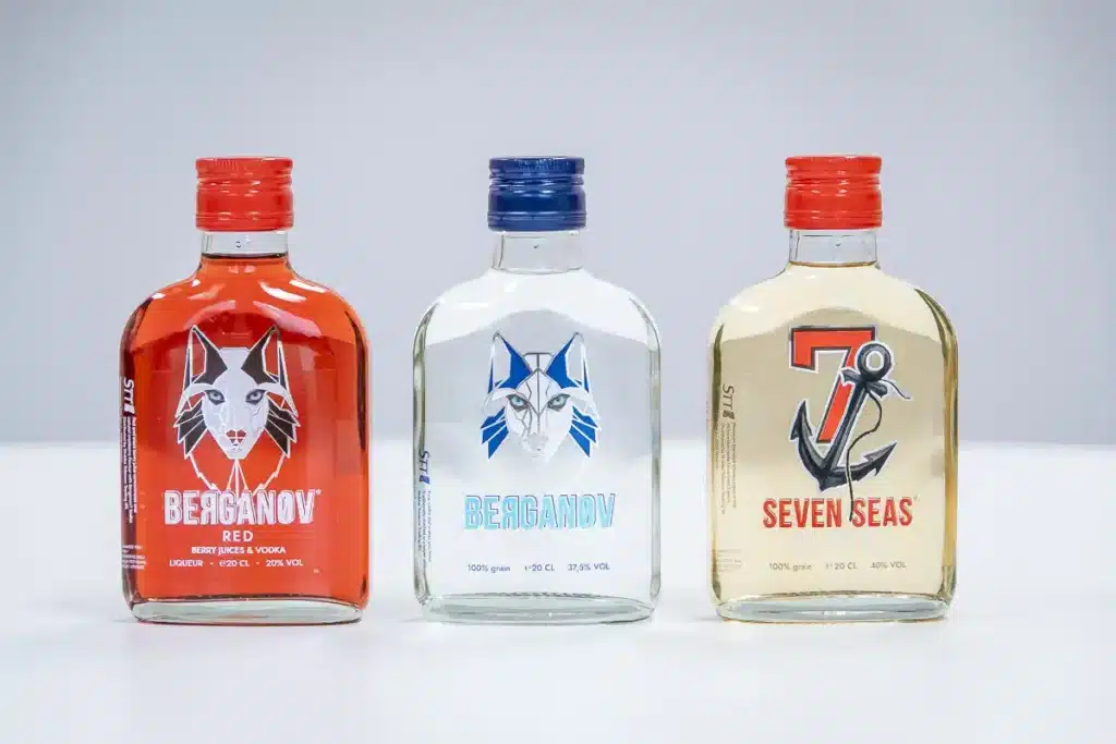 Drie flesjes drank van Berganov en Seven Seas met wolf- en ankerlogo's op de etiketten.