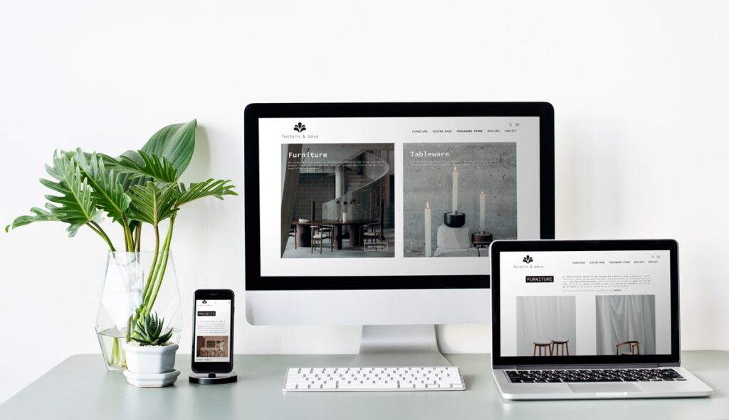 Een moderne werkruimte met daarop de website van 'fontein & bova' weergegeven op een desktopcomputer, een laptop en een smartphone. De website toont categorieën voor meubels en serviesgoed.