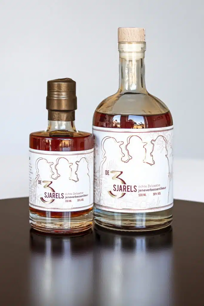 Twee flessen likeur van Stokerij eenvoud genaamd "De 3 Sjarels", met een fles van 500 ml en een van 200 ml, gepresenteerd naast elkaar.