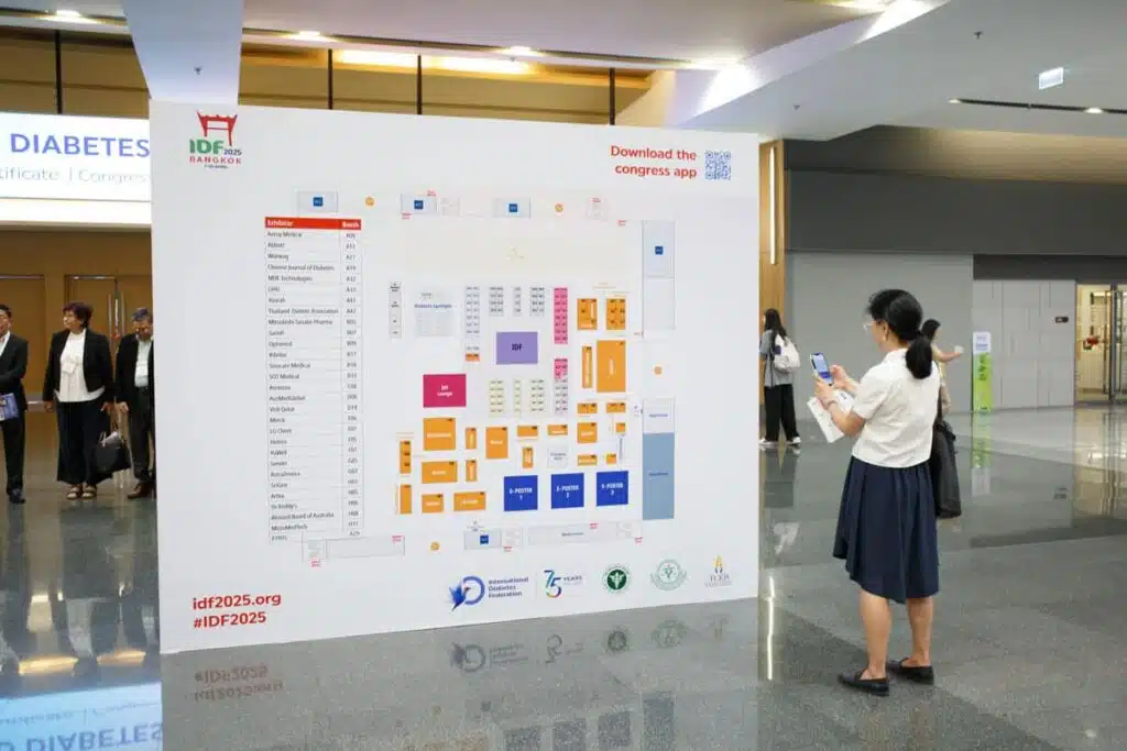 Vrouw bekijkt plattegrond van IDF 2025 diabetes congres in Bangkok met standlocaties en programma-informatie