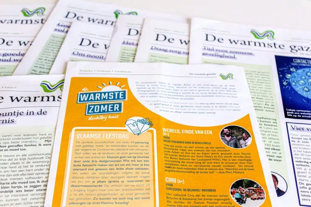 Verschillende edities van "De warmste gazette" van Wichelen met in het midden een oranje pagina over "De Warmste Zomer."