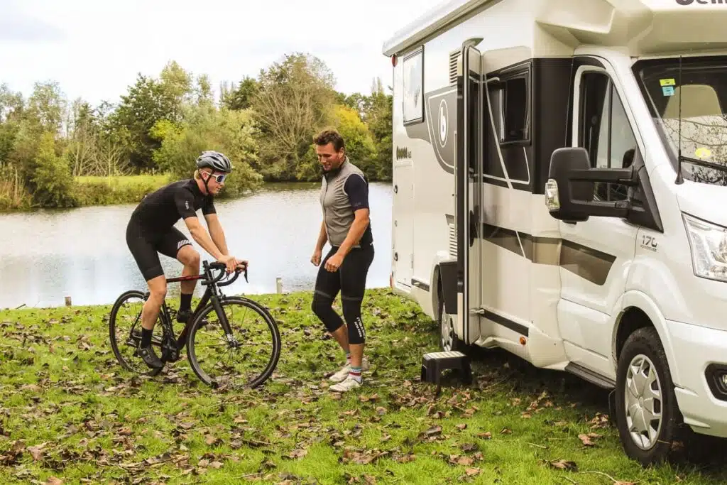 Wielrenners naast een Reislust camper in een groene omgeving