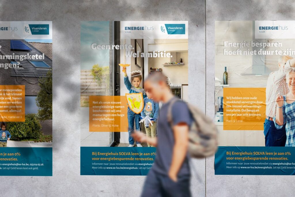 Energiehuis Familieposter voor Solva: Een reeks posters aan een muur, die energiebesparende initiatieven promoten. De posters tonen beelden van gezinnen en individuen met motiverende teksten zoals "Geen rente. Wel ambitie." Het ontwerp gebruikt een mix van blauw en oranje kleuren om warmte en energie-efficiëntie te benadrukken.