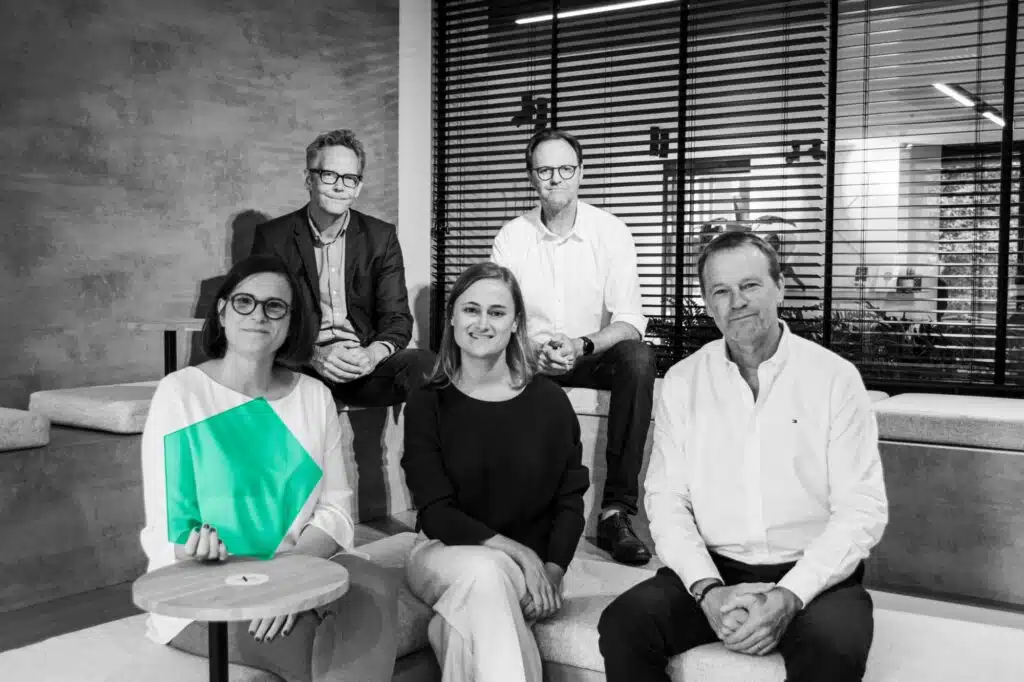 Zwart-wit groepsfoto van WHYFIVE team met een focus op samenwerking en bedrijfsidentiteit, elk met een groene hexagon.