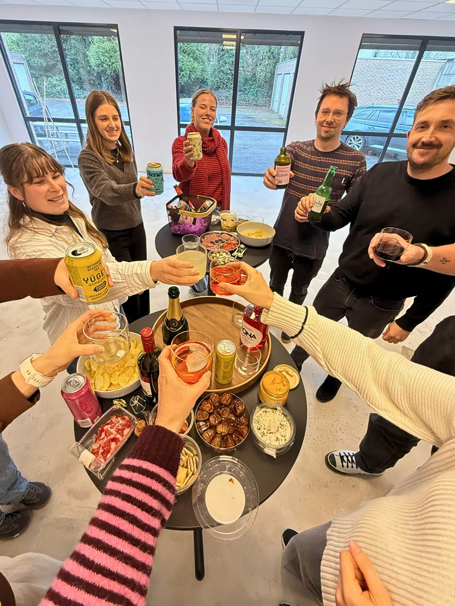 Graviteit team viert feest in kantoor met hapjes, drankjes en collega's rond tafel tijdens sociale bijeenkomst