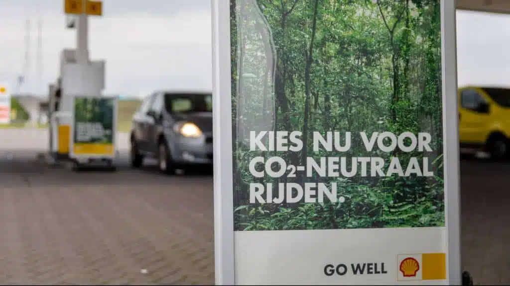 Foto van een Shell-advertentie bij een tankstation met de tekst "Kies nu voor CO2-neutraal rijden" en een afbeelding van een groene bosrijke omgeving.