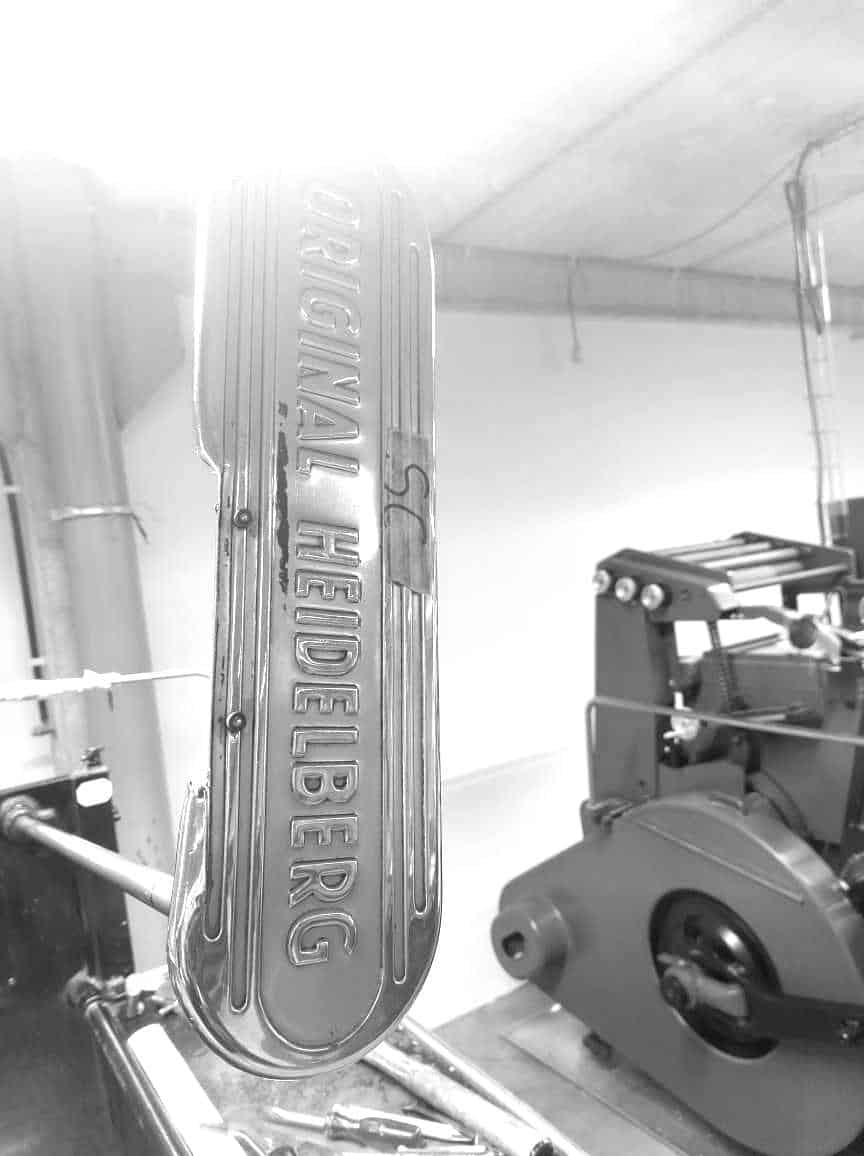 "Original Heidelberg" logo en een Heidelberg drukpersmachine in de achtergrond.