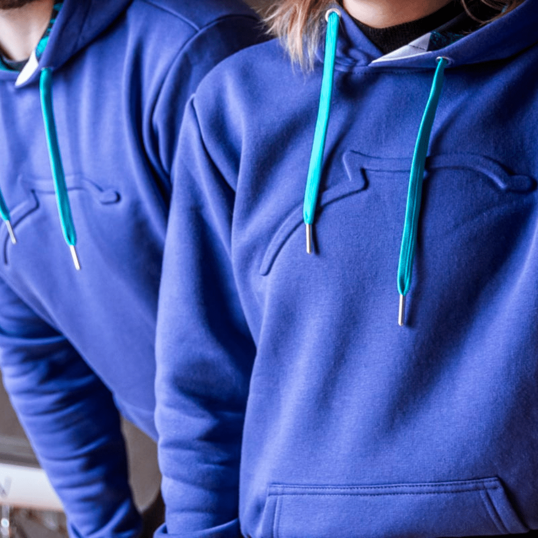 Twee medewerkers in paarse BeMedico hoodies met turquoise koordjes, onderdeel van de eindejaarscampagne in samenwerking met S