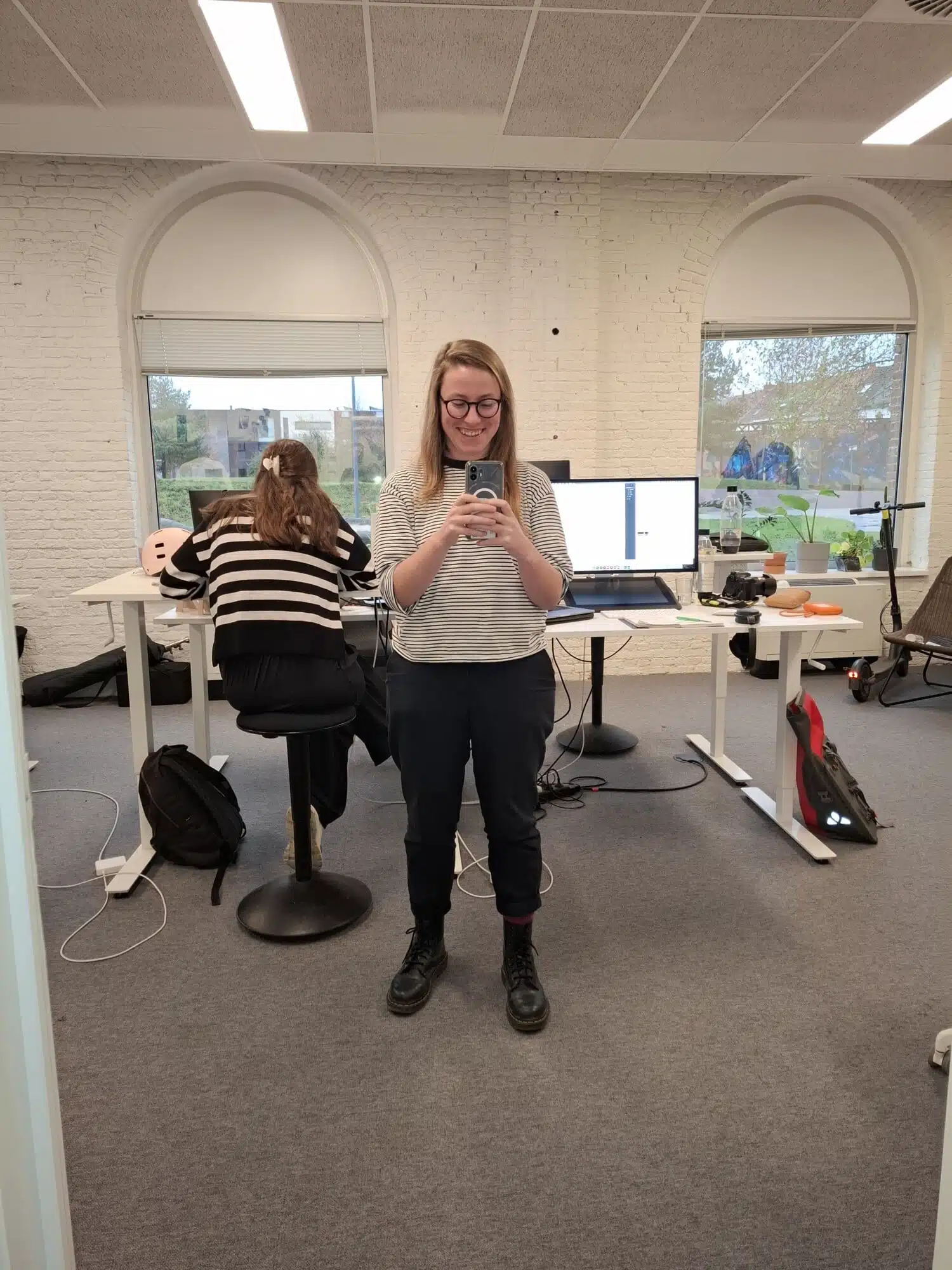 Jana, stagiair contentcreatie, gebruikt haar telefoon op kantoor bij Graviteit met collega aan bureau