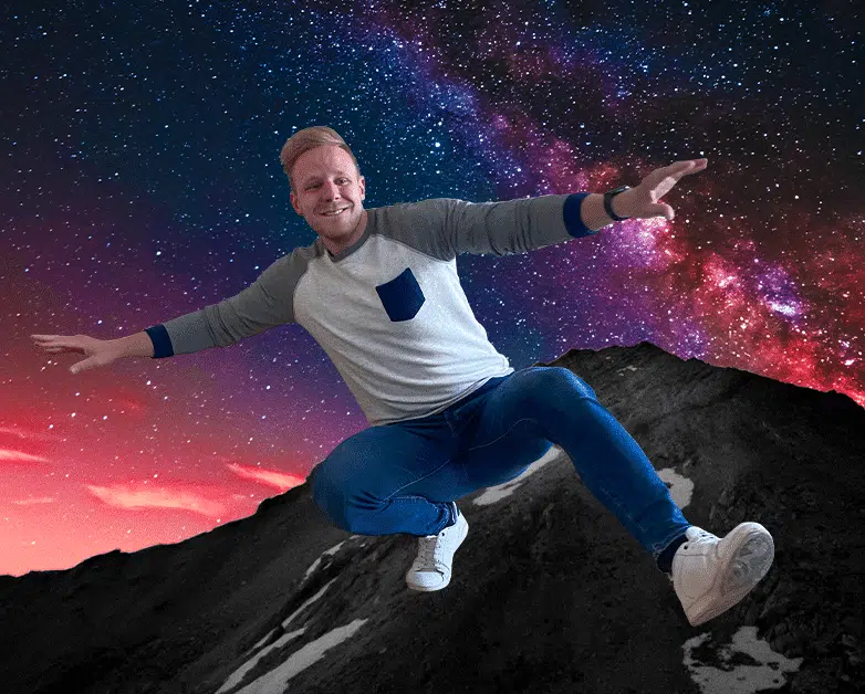 Stagiair Alex poseert speels alsof hij zweeft op een berg, met een kleurrijke sterrenhemel op de achtergrond.