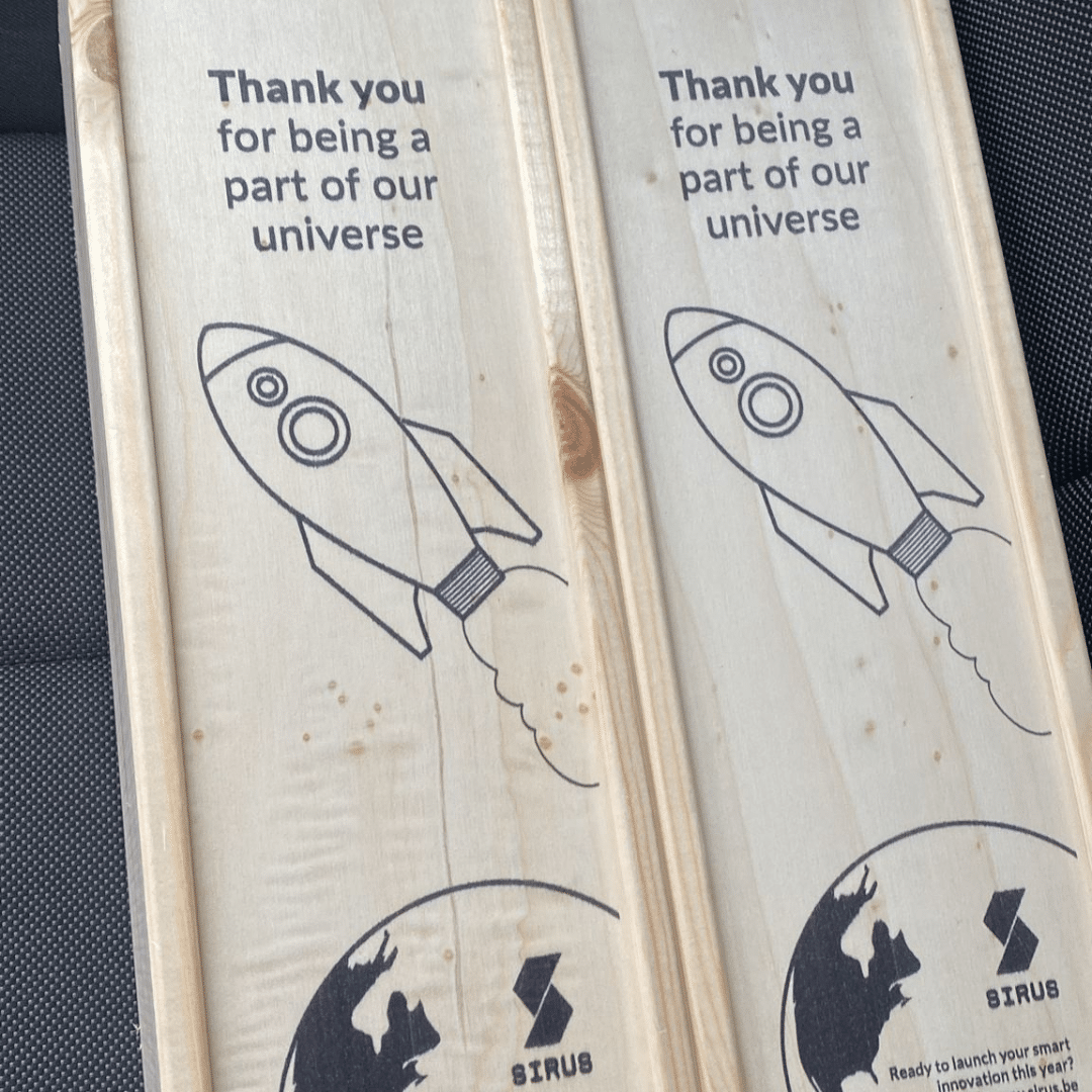 Houten geschenkdozen met een illustratie van een raket en de tekst "Thank you for being a part of our universe" van Sirus.