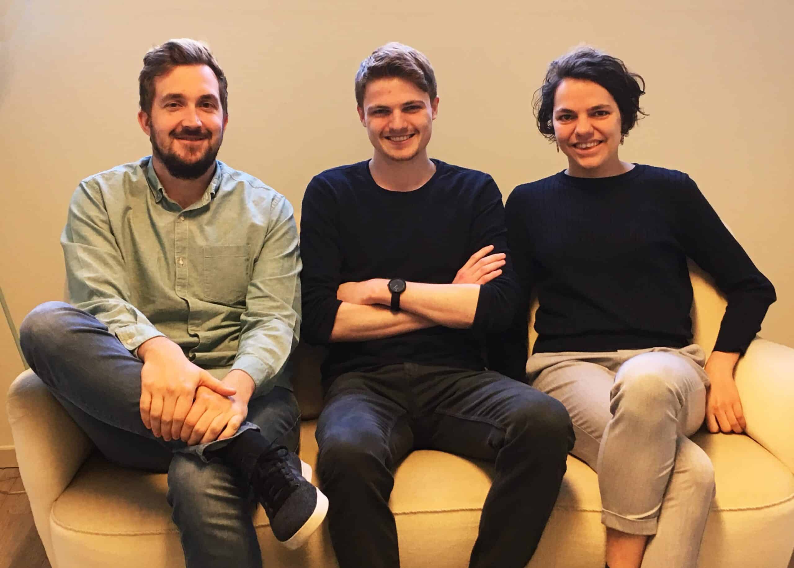 Een groepsfoto van Frank Mertens, Kevin en Ines Maroye die op een bank zitten, lachend naar de camera.