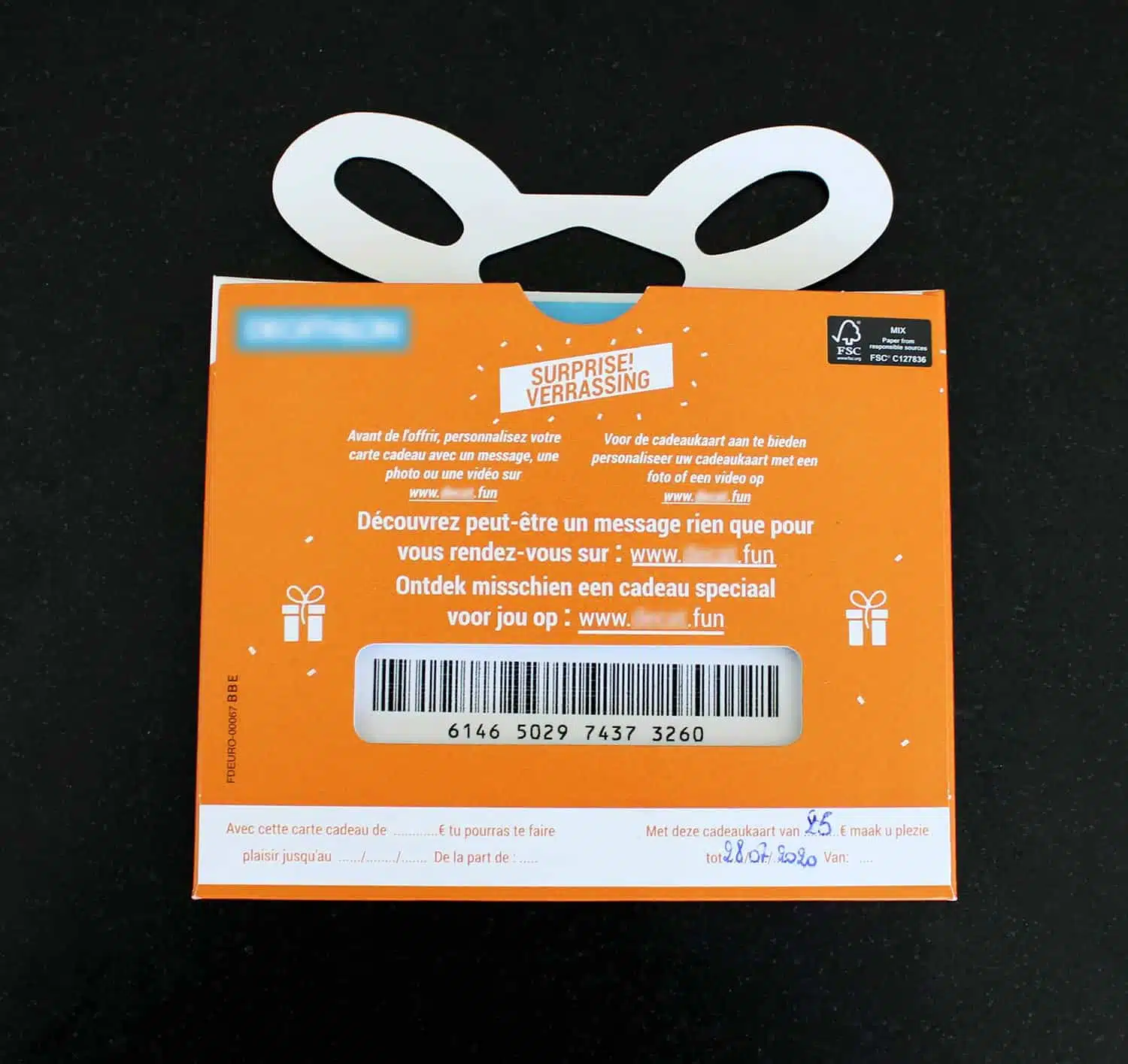 Achterkant van een oranje cadeaukaart verpakking met handvat en tekst in het Nederlands en Frans over het personaliseren van de kaart en een cadeau verrassing.