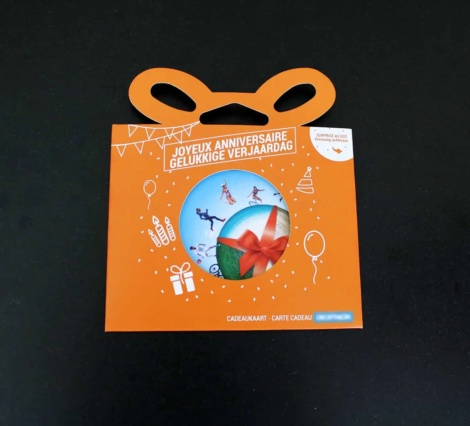 Oranje cadeaukaart verpakking met de tekst 'Joyeux Anniversaire' en 'Gelukkige Verjaardag', versierd met ballonnen, feesthoedjes, en geschenkiconen.