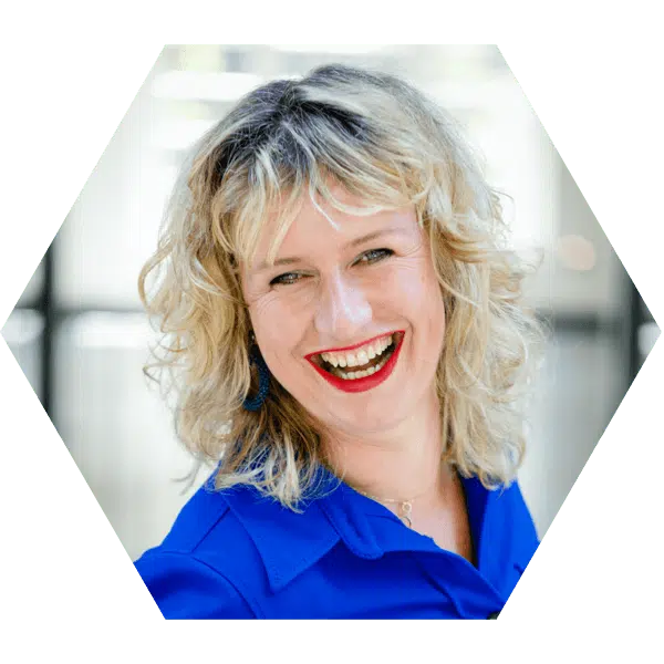 social media ondernemer congres Een hexagonale foto van een vrouw met licht krullend blond haar, een felblauwe blouse en een brede glimlach, wat een energieke en vriendelijke sfeer weergeeft.