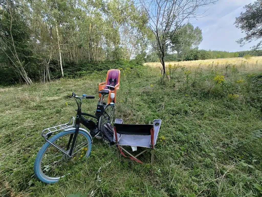 Pieter van Graviteit zit in een kampeerстoeltje in de Gentbrugse Meersen, naast zijn fiets met kinderzitje, omgeven door natu