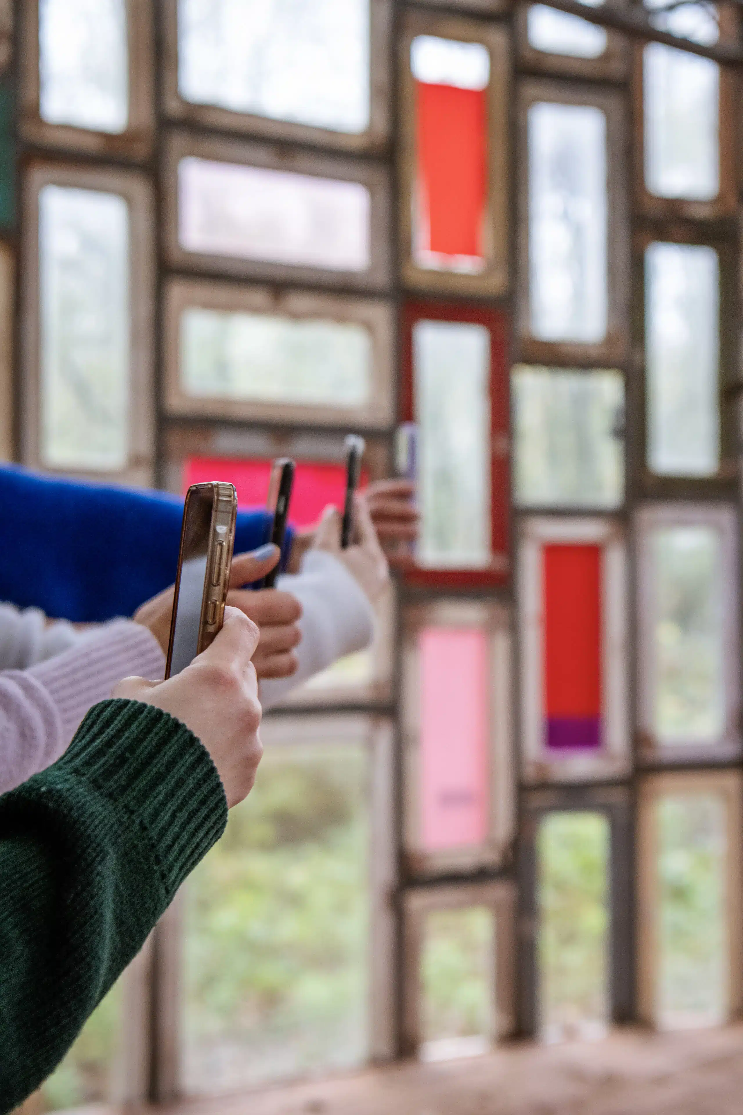 Bezoekers fotograferen een kleurrijke installatie van oude raamkozijnen met smartphone tijdens Graviteit rebrandingshoot