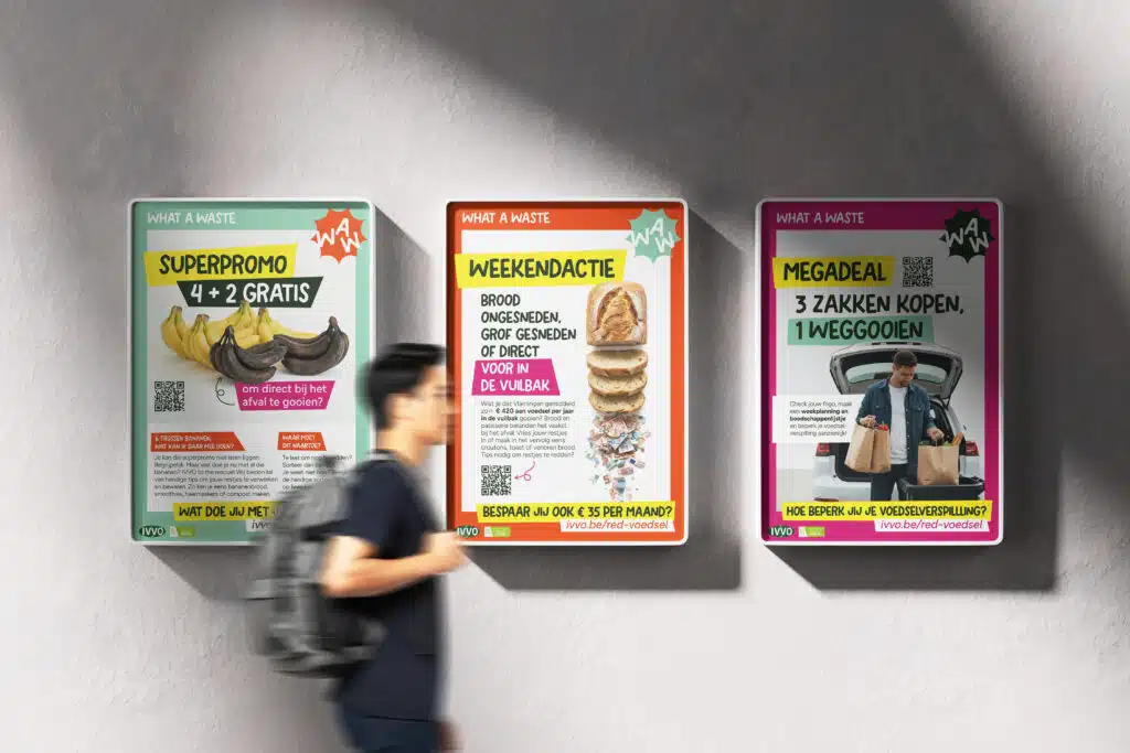 Drie kleurrijke IVVO 'What a Waste'-campagneposters over voedselverspilling aan een muur, voorbijlopende man met rugzak