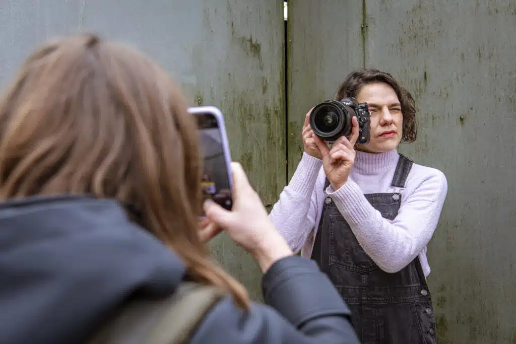 Graviteit creatief teamlid fotografeert met DSLR-camera terwijl collega een foto neemt met smartphone tijdens rebranding shoo